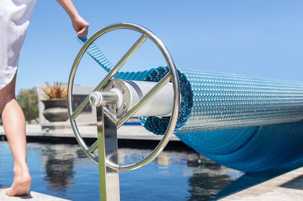 Pool Cover being unrolled over pool, Contact Daisy Pool Covers & Rollers. 